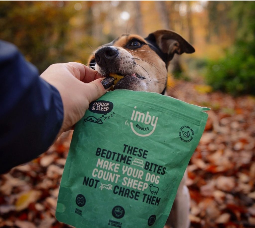 Een hond die vrolijk een hondensnoepje van Imby Pet Food eet.