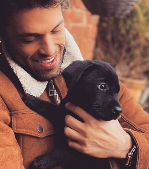 Een man die een puppy hond in zijn armen draagt.