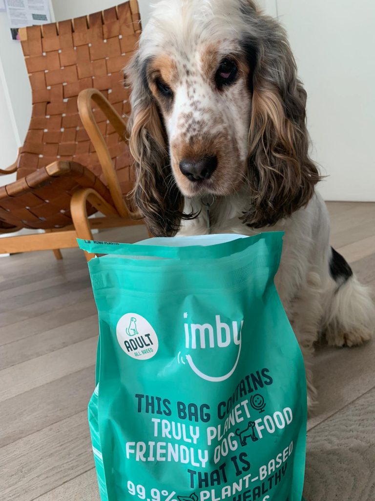 Een hond die direct uit een zak hondenvoer van Imby Pet Food eet.